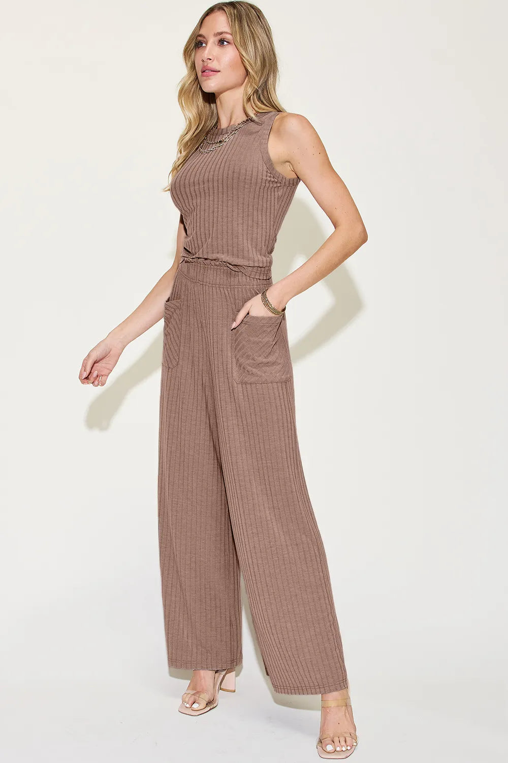 Woman wearing a brown ribbed jumpsuit on a white background