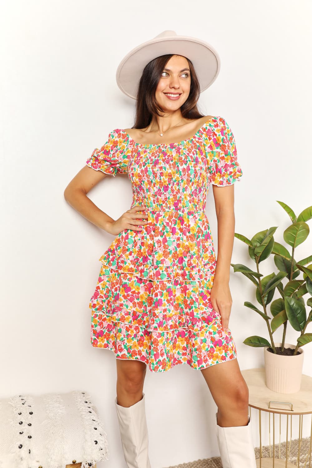 Woman wearing a colorful dress with a white hat indoors
