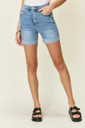 Person wearing light blue denim shorts on a plain background