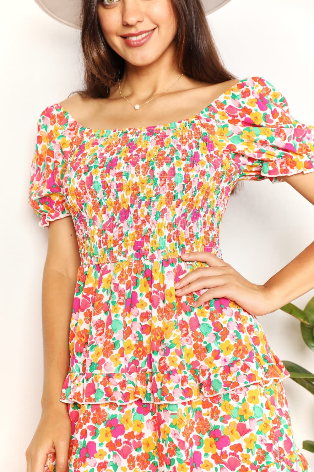 Woman wearing a colorful floral dress against a white background