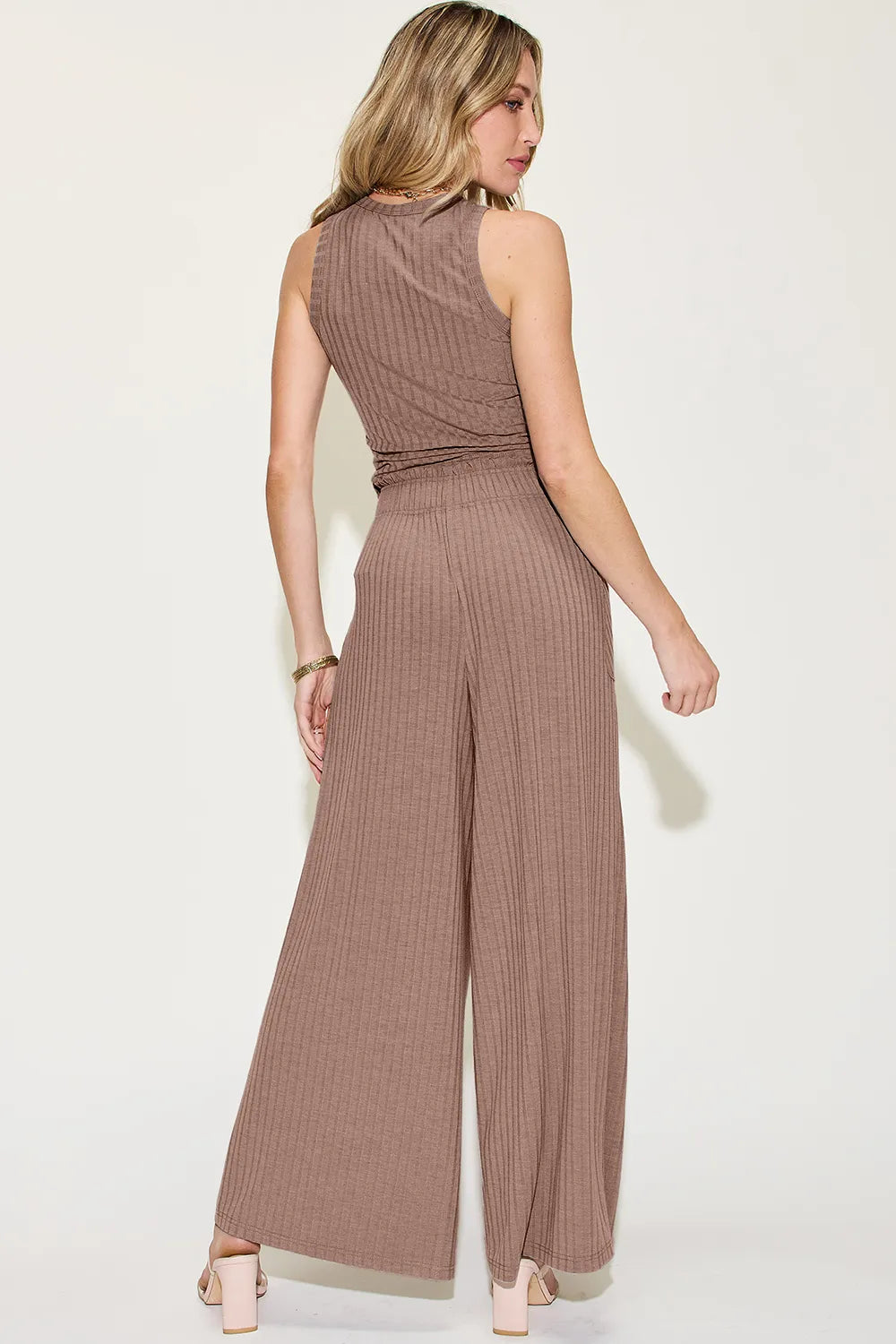 Woman wearing a brown ribbed jumpsuit on a white background