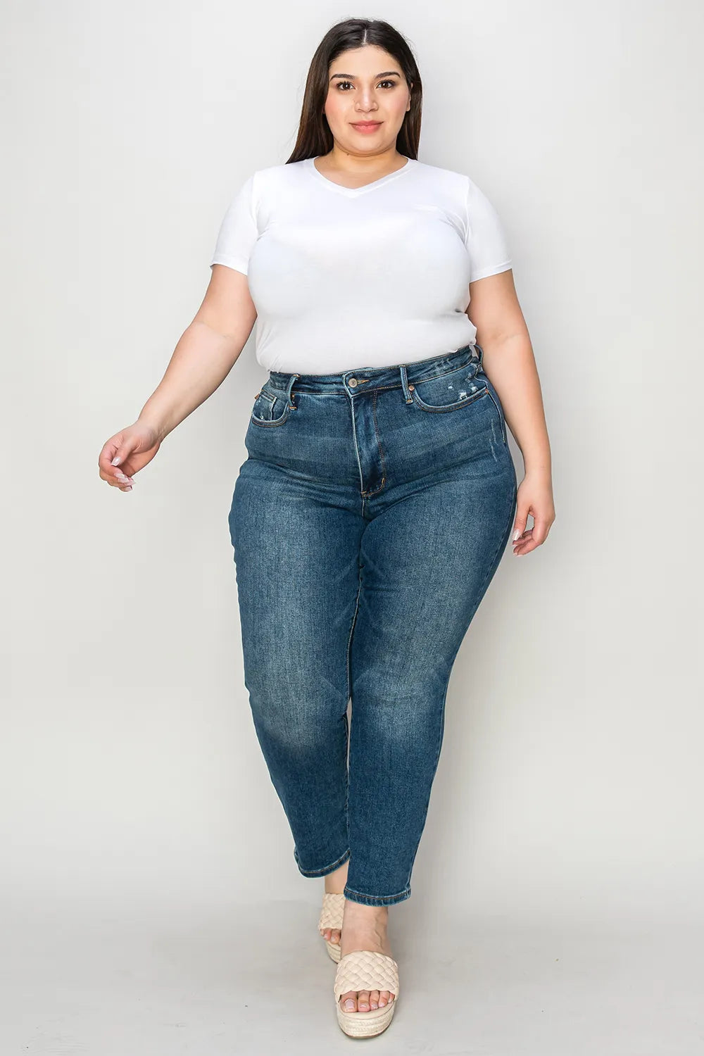 Woman wearing a white t-shirt and blue jeans on a plain background
