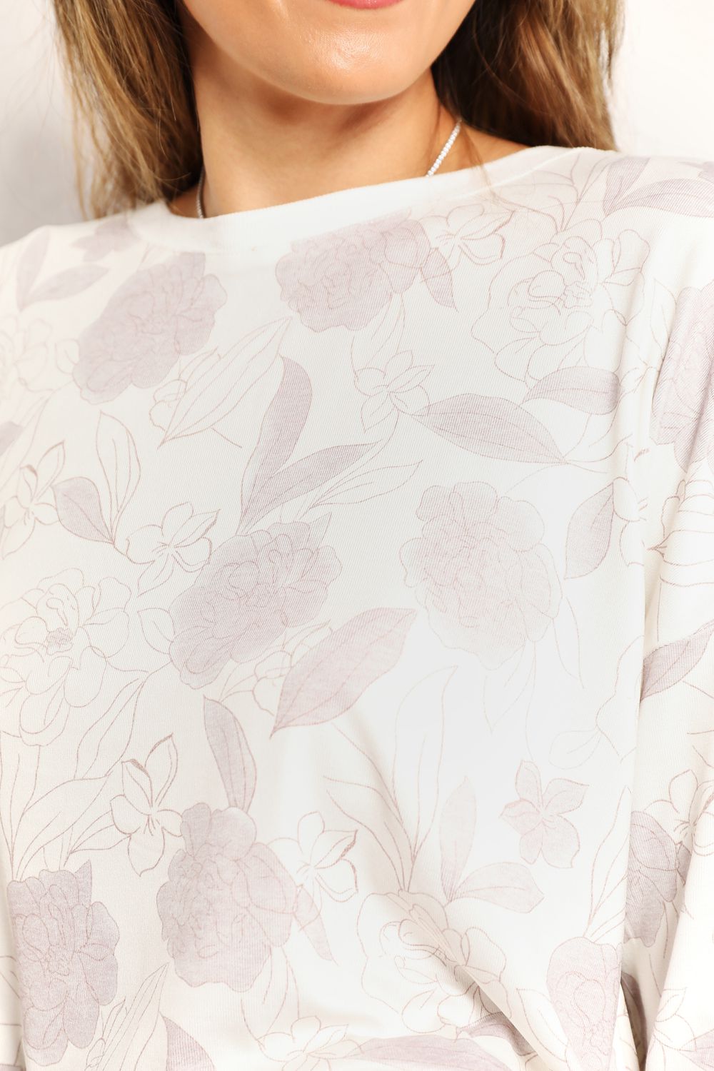 Close-up of a white blouse with floral patterns on a plain background