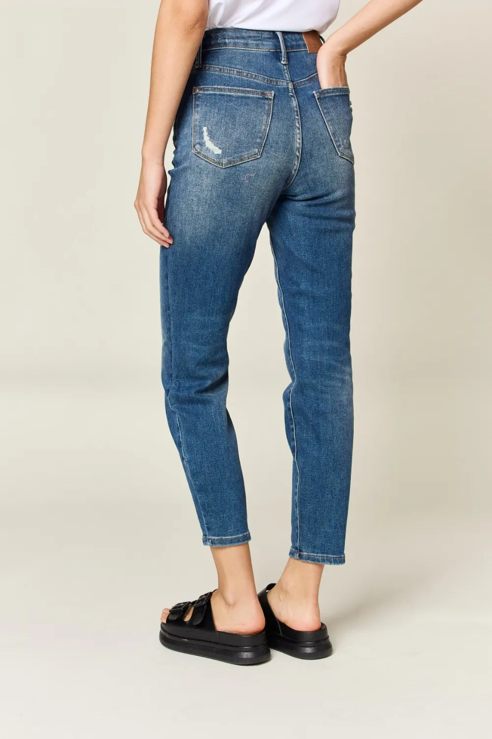Person wearing blue jeans on a plain background